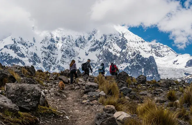 Hikers on a rocky trail below the Ausangate glacier