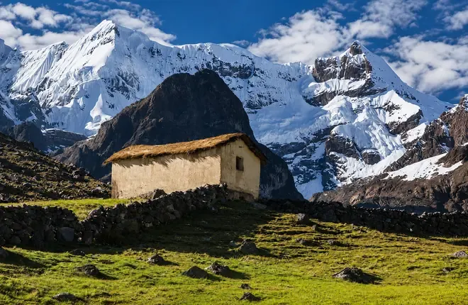 Stone hut with a thatched roof under the snow peaks of Ausangate