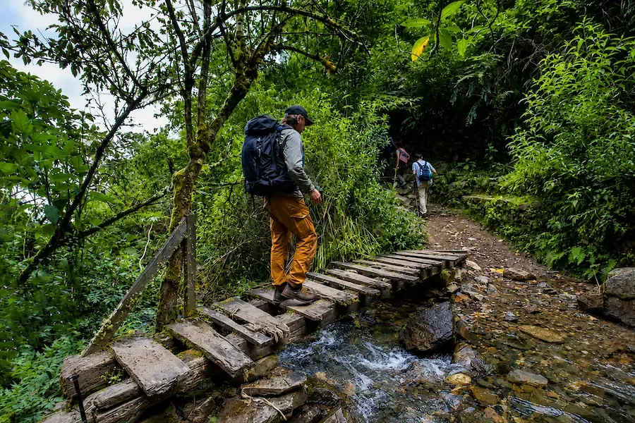 Hikers crossing a wooden bridge over a stream on the Choquequirao trail