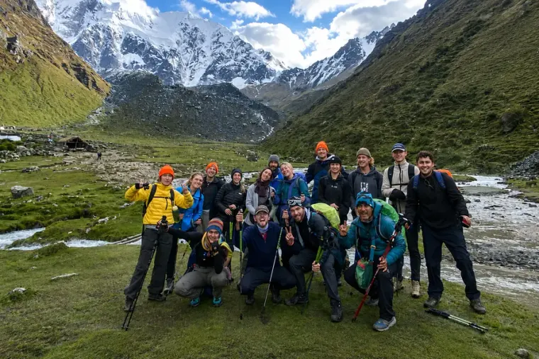 Trekking group with poles beside a river below the Salkantay massif