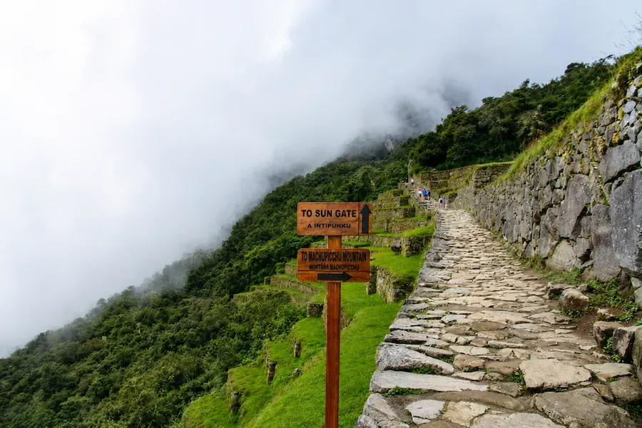 Wooden sign pointing to the Sun Gate beside the stone path