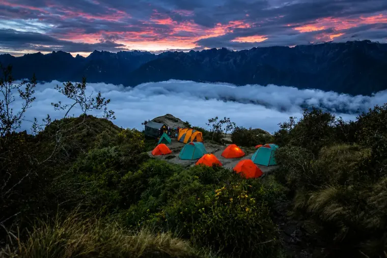 Tents glowing at dusk at a camp above the clouds