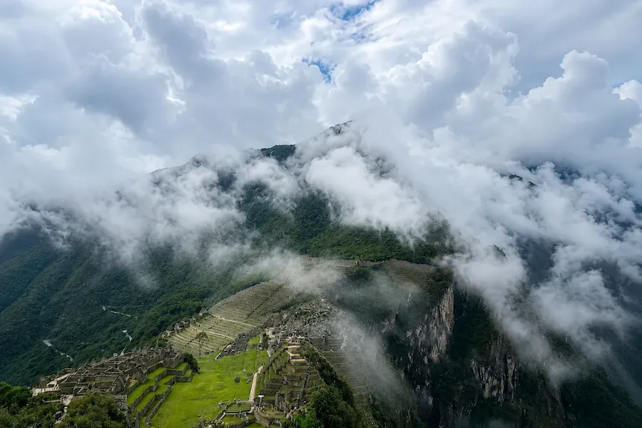 Machu Picchu seen from above with clouds drifting across it