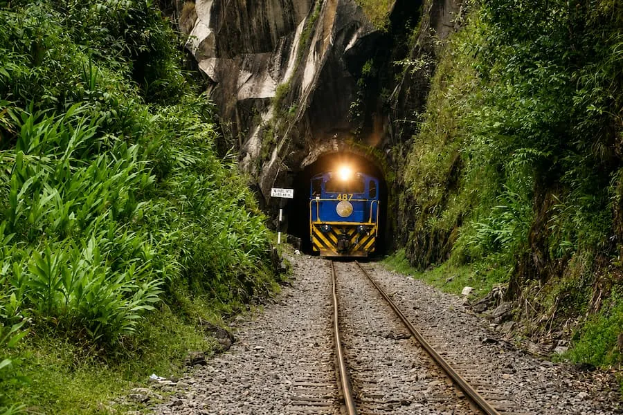 Train coming out of a rock tunnel on the line to Machu Picchu