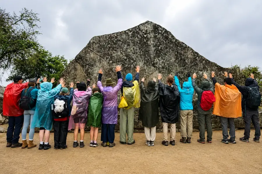 Visitors in bright rain ponchos in front of the Sacred Rock at Machu Picchu