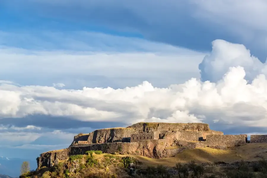 The fort of Puca Pucara on its hilltop under towering clouds