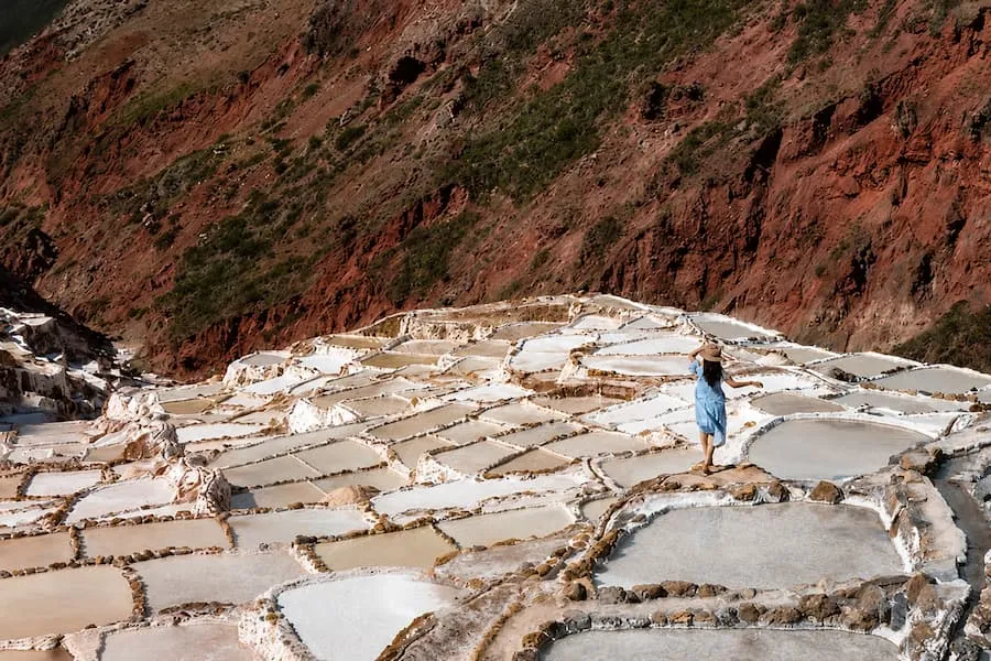 Traveler walking among the white pools of the Maras salt pans