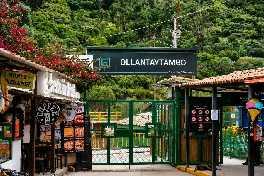 Green gate of Ollantaytambo train station with bougainvillea and small shops