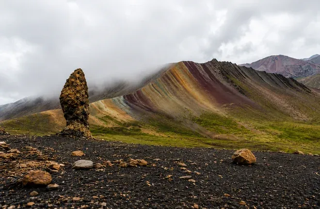 Rock spire of the stone forest beside a colored ridge in the mist