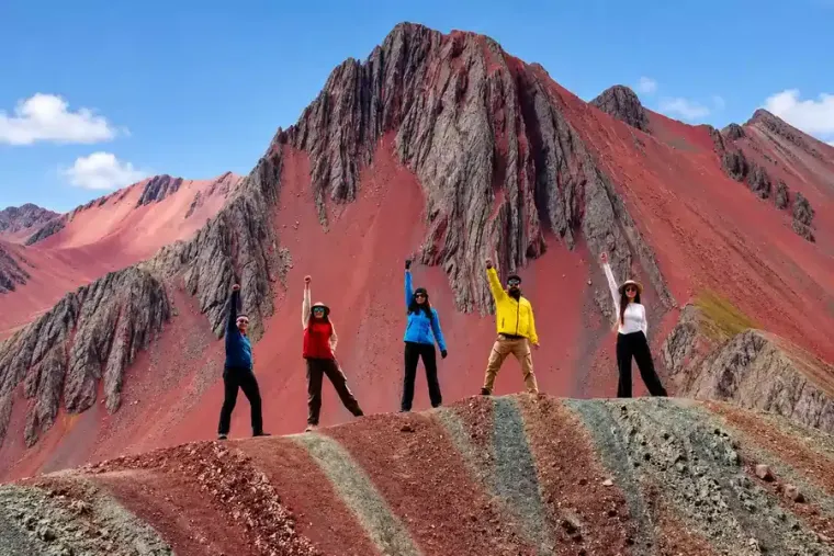 Group of hikers celebrating on the colored ridge of Pallay Punchu