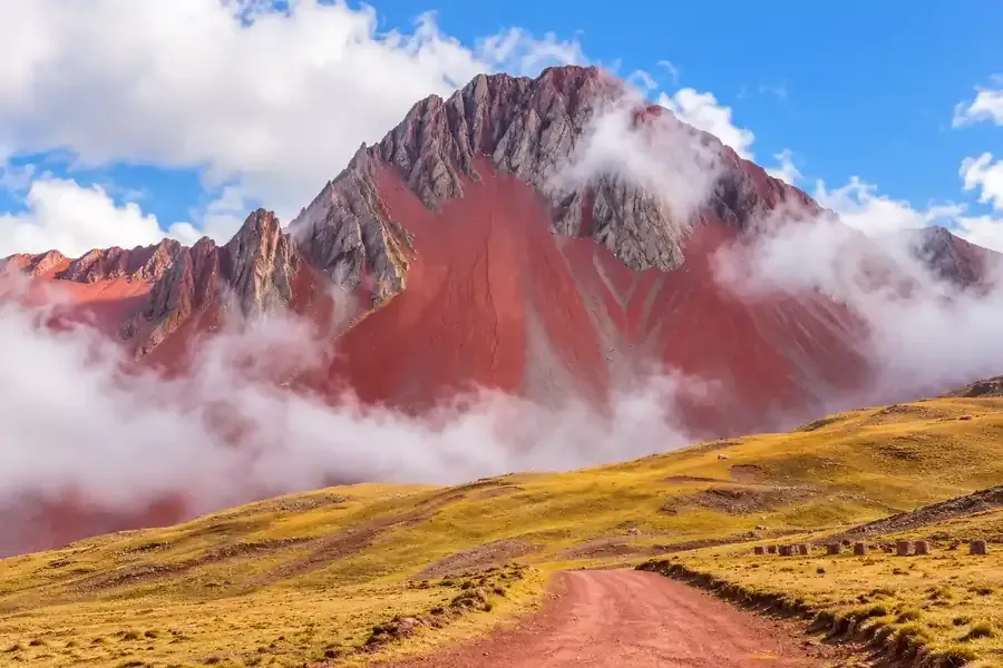 Sharp reddish peaks of Pallay Punchu among the clouds