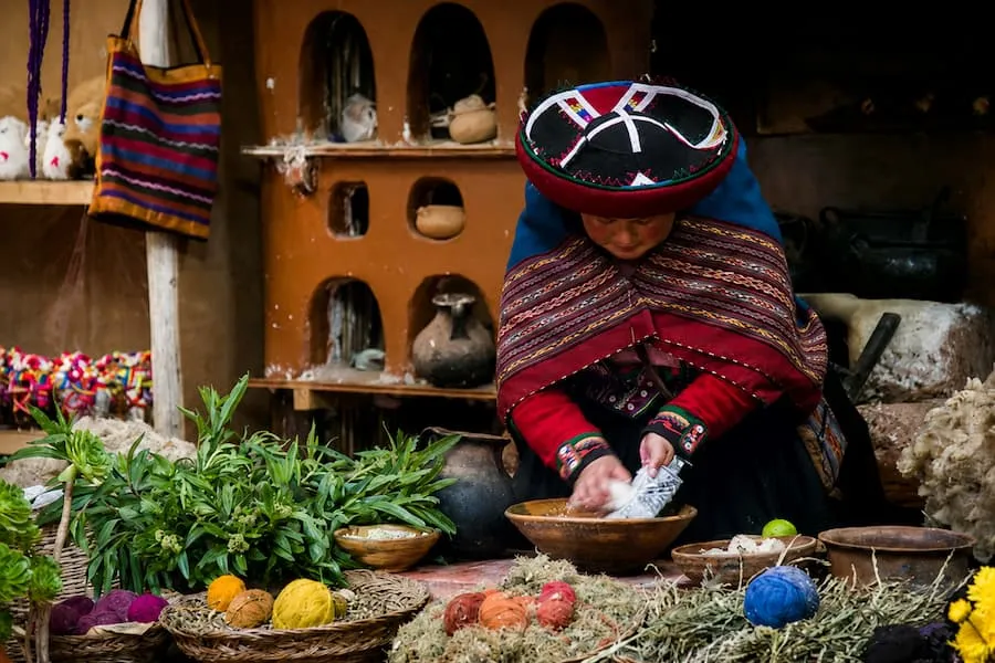 Quechua weaver in traditional dress showing natural dyes in Chinchero