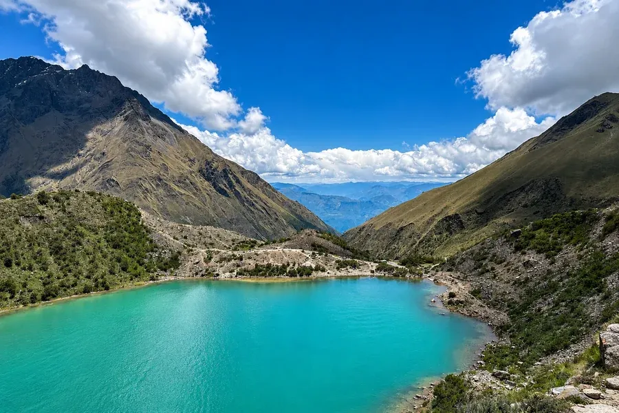 Turquoise Humantay Lake between steep slopes on a clear day