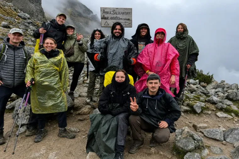 Trekking group in rain ponchos at the Salkantay Pass sign